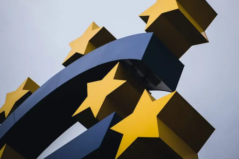 Close-up detail of a sculpture in the shape of a euro symbol, surrounding by five yellow stars