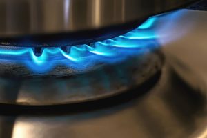 Close-up of a saucepan on a cooker hob lit with a blue gas flame